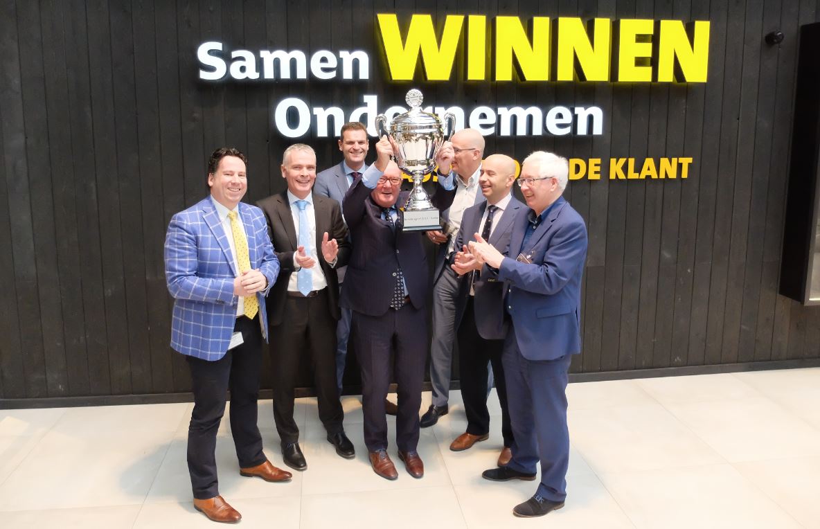 Karel van Eerd trots met de beker temidden van (een deel) van zijn management team