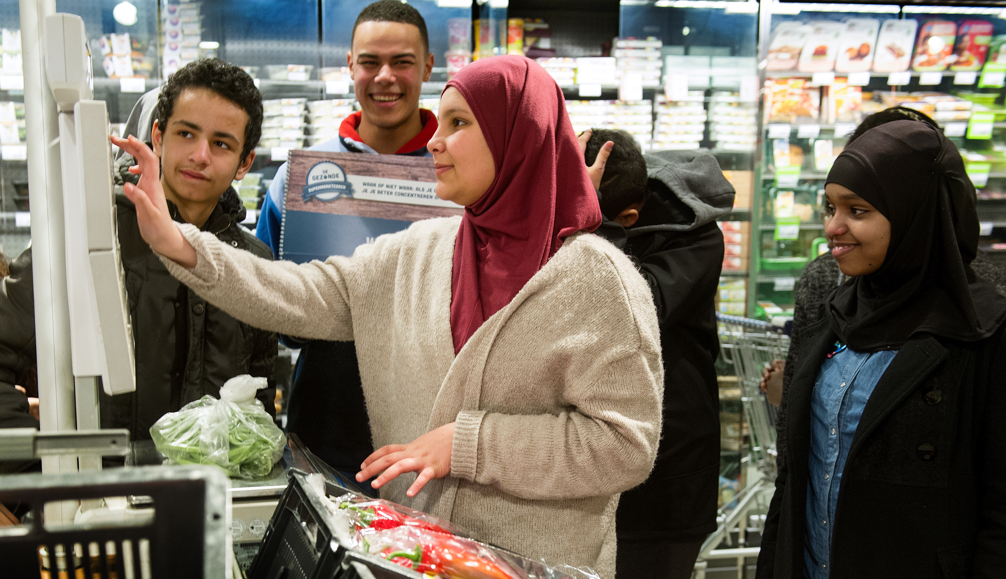Supermarktcoach Damian van Albert Heijn in de Kinkerstraat laat scholieren wegen hoeveel 2 ons groente is.