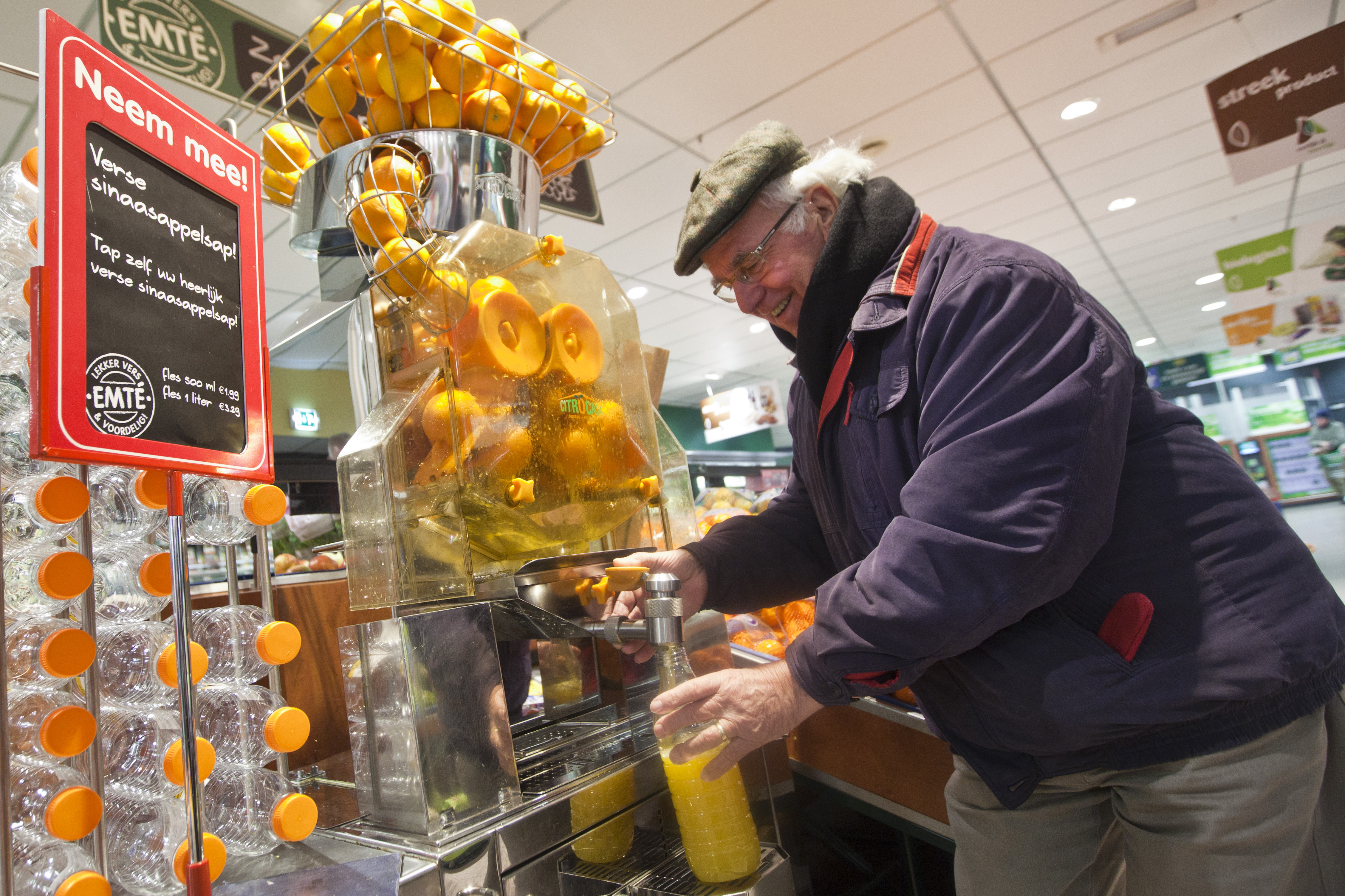 Een klant tapt vers sinaasappelsap. Foto: Koos Groenewold