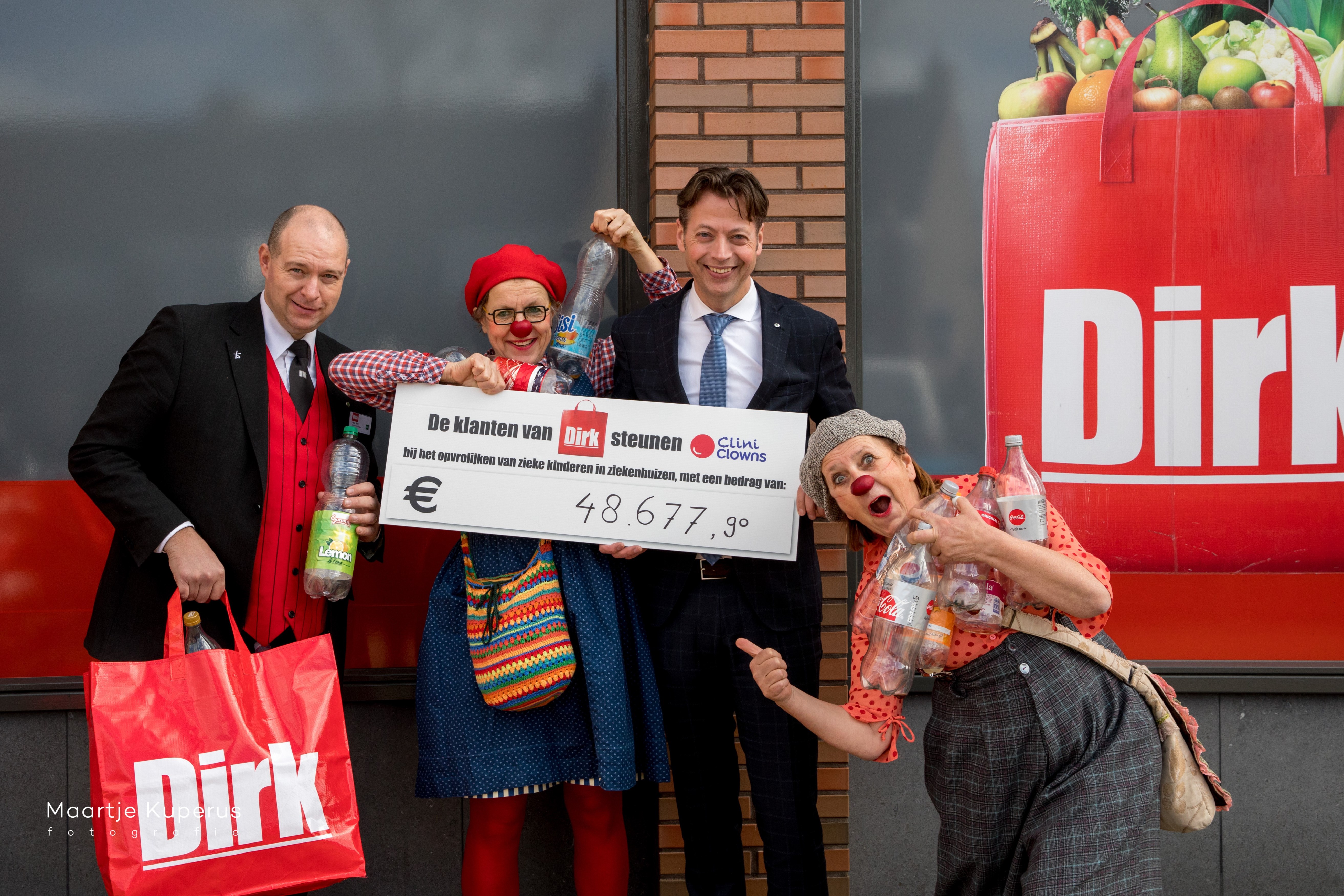 Marcel Huizing overhandigt, samen met Supermarktmanager Max Belt, in Ter Aar namens alle klanten van Dirk van den Broek de opbrengst van de statiegeldactie aan CliniClowns Nop & Neel. 