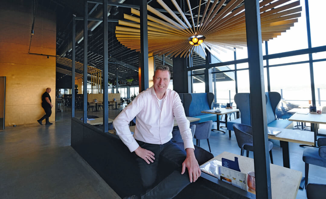 Henri Offerein met aan het plafond een door hemzelf ontworpen en gemaakte ‘zon’. Foto: Distrifood