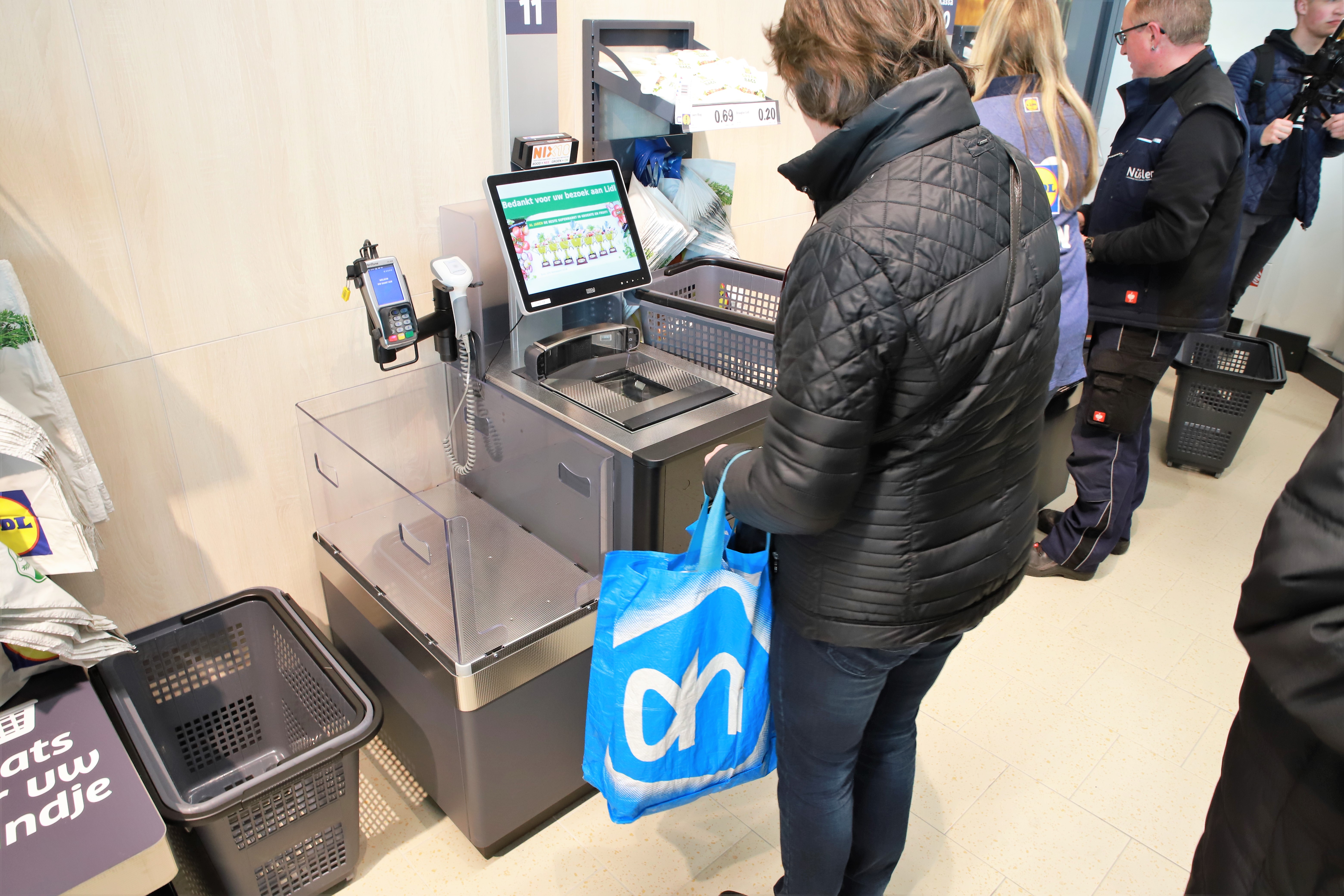 Klant met AH tas aan het zelfscannen bij Lidl Huizen