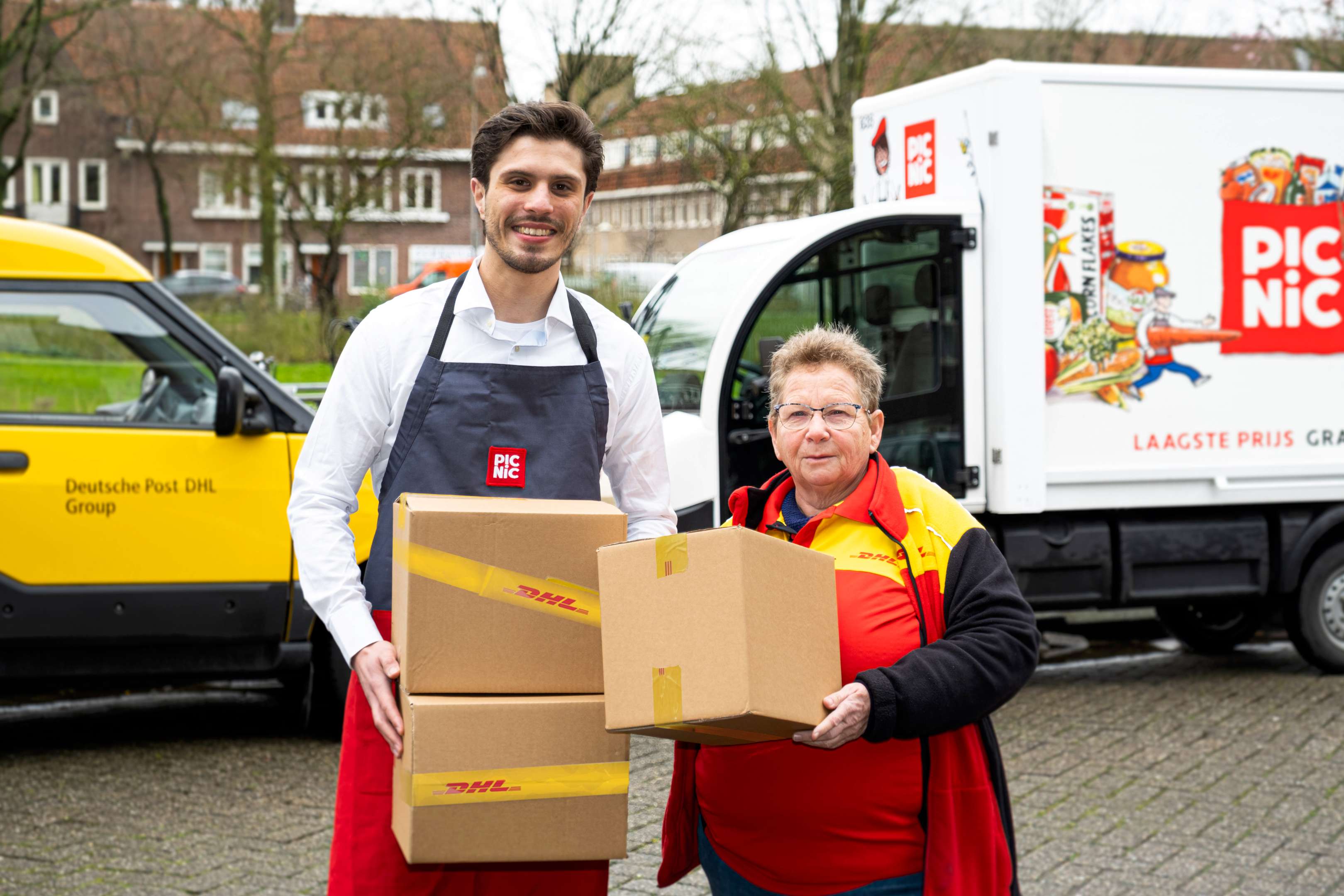 De elektrische wagentjes van onlinesupermarkt Picnic halen pakketjes van DHL op bij klanten thuis. Door die samenwerking kunnen ze bijvoorbeeld retourzendingen van webwinkels meegeven als de boodschappen worden bezorgd. Foto: Picnic.