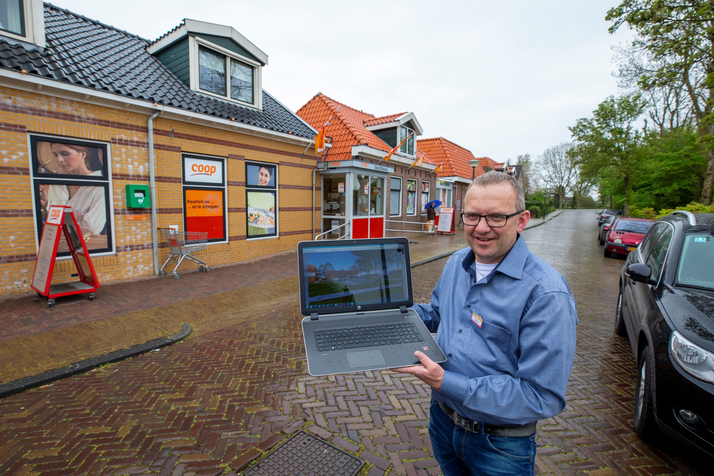 Richard Langeland voor de winkel die uit aan elkaar gebouwde panden bestaat. Op de laptop een impressie van de nieuwbouw.
Foto: Anne van der Woude