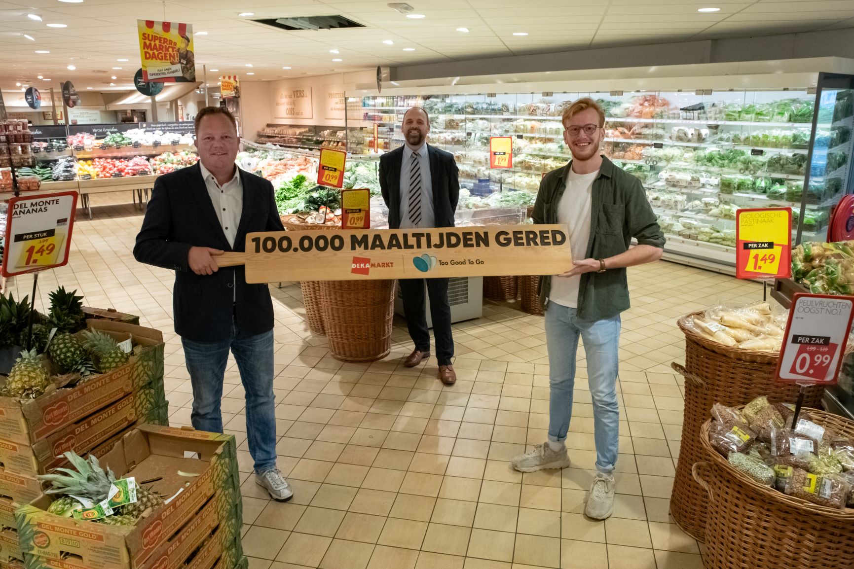 Uit handen van Wouter Hummel (l), formulemanager bij Dekamarkt, en Falk Holtslag, Key Account Specialist bij Too Good To Go, ontving het filiaalteam dat zich bezig houdt met het samenstellen van de boxen een 1,5 meter lange broodplank. 