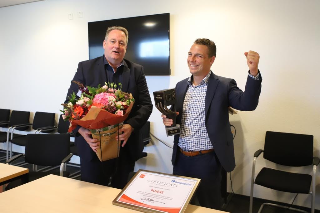 Harrie Westra (links) , destijds werkzaam bij Poiesz, neemt bloemen in ontvangst na de winst van de formule in het GfK Versrapport. Foto: Distrifood