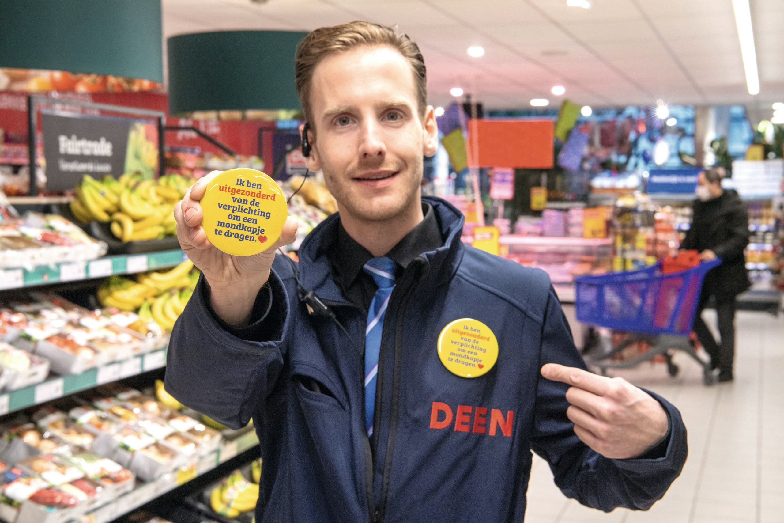 Deen werkte met buttons voor medewerkers die om medische redenen geen mondkapje kunnen dragen. Dat mondkapje verdwijnt als laatste zichtbare element van de coronapandemie in de supermarkten Foto: Cor Salverius