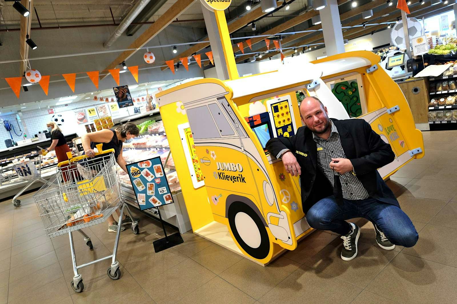 Dennis Oude Alink bij de speelhoek in de vorm van een hippiebus. ‘We willen dat kinderen erom zeuren om hier boodschappen te doen.’ Foto: Distrifood
