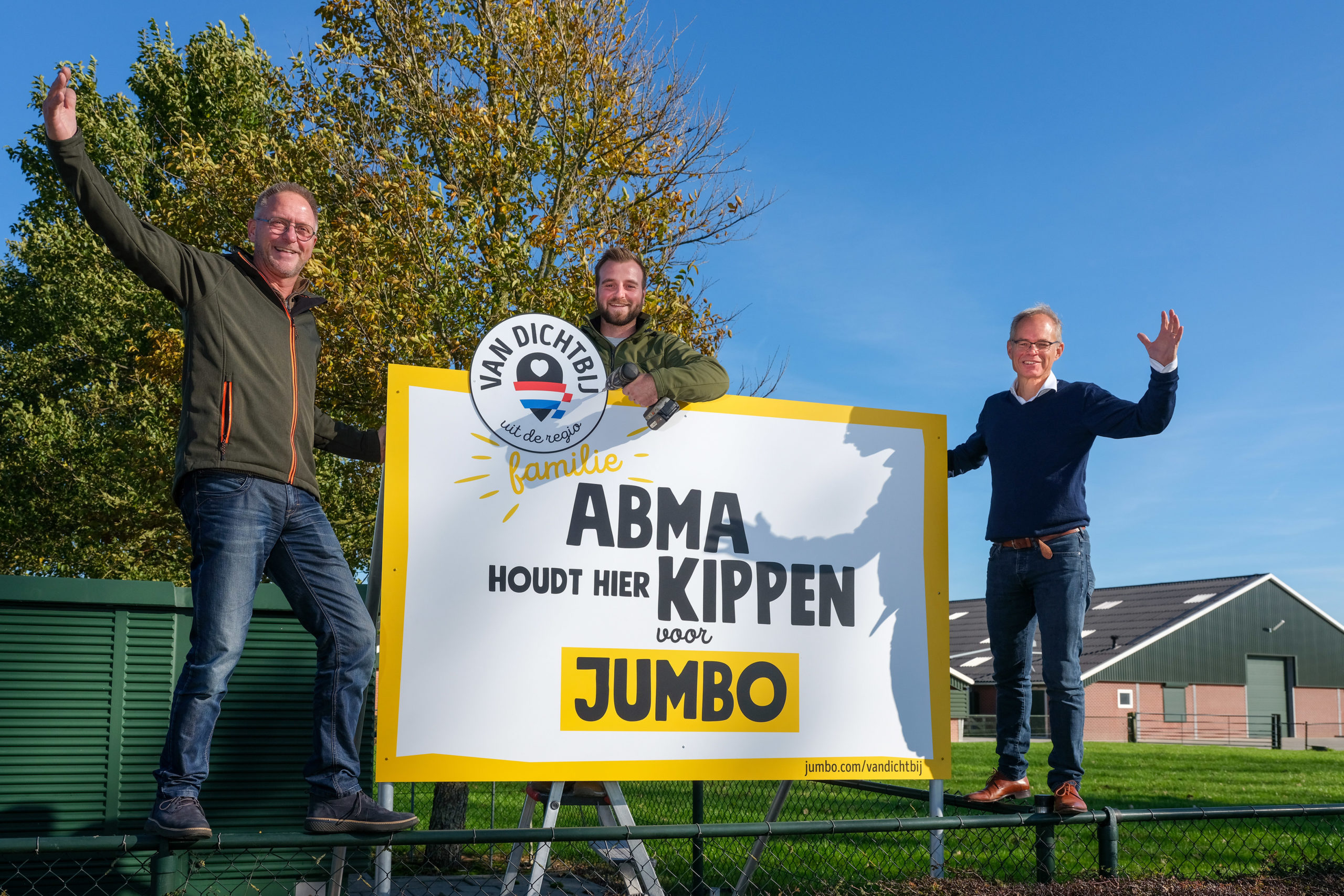 Cees van Vliet, operationeel directeur van Jumbo (rechts), plaatst het bord bij pluimveehouder Abma in Groningen. Zoon Jesse neemt binnenkort het bedrijf over van zijn vader Ruurd. De familie Abma gaat over van Nieuwe Standaard Kip naar 1-ster Beter Leven-kip. De nieuwe NSK wordt nu voor alle verse kip verruilt voor het Beter Leven keurmerk. Foto Jumbo