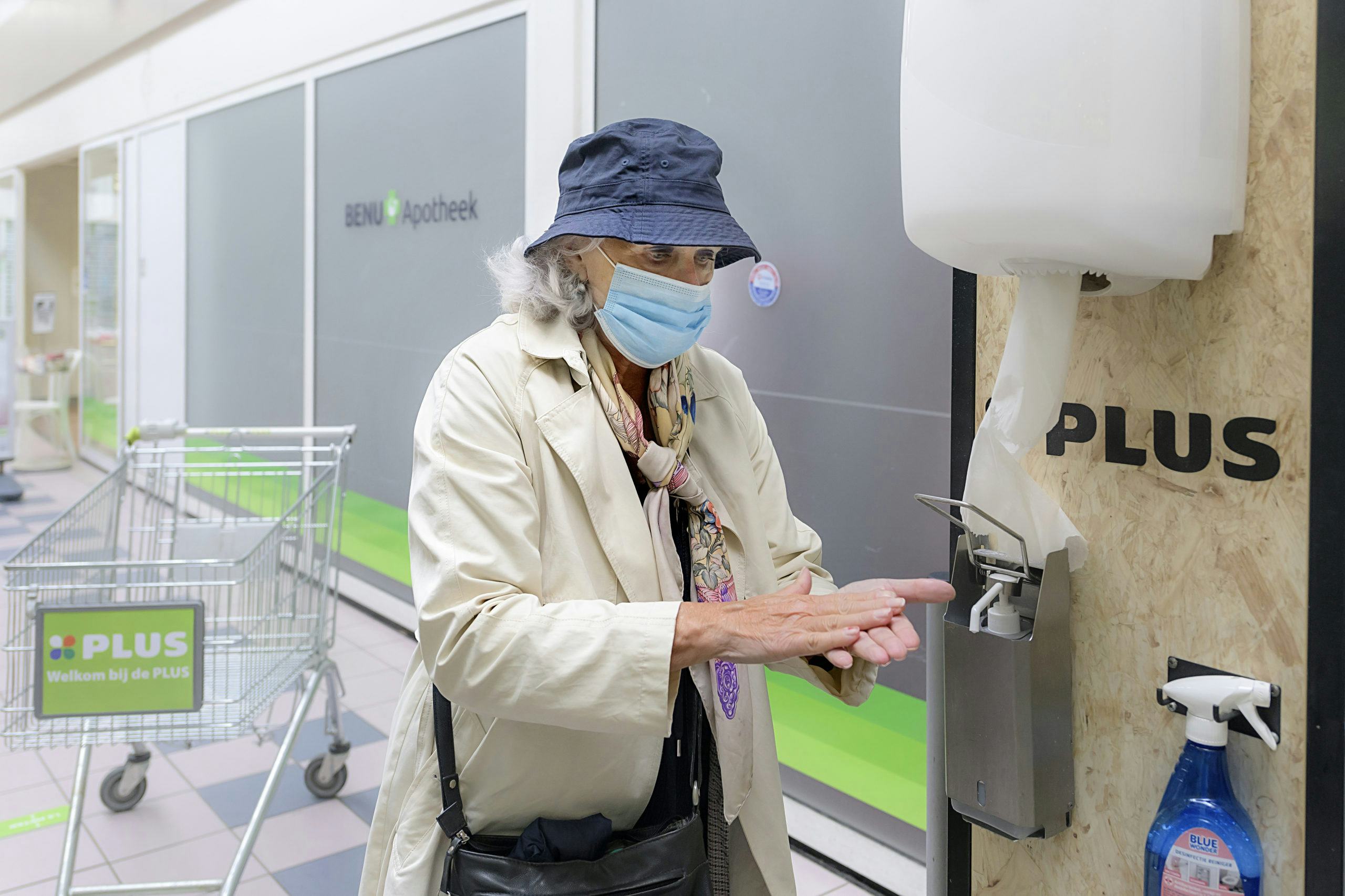 Een vrouw desinfecteert haar handen bij Plus. Foto: ANP