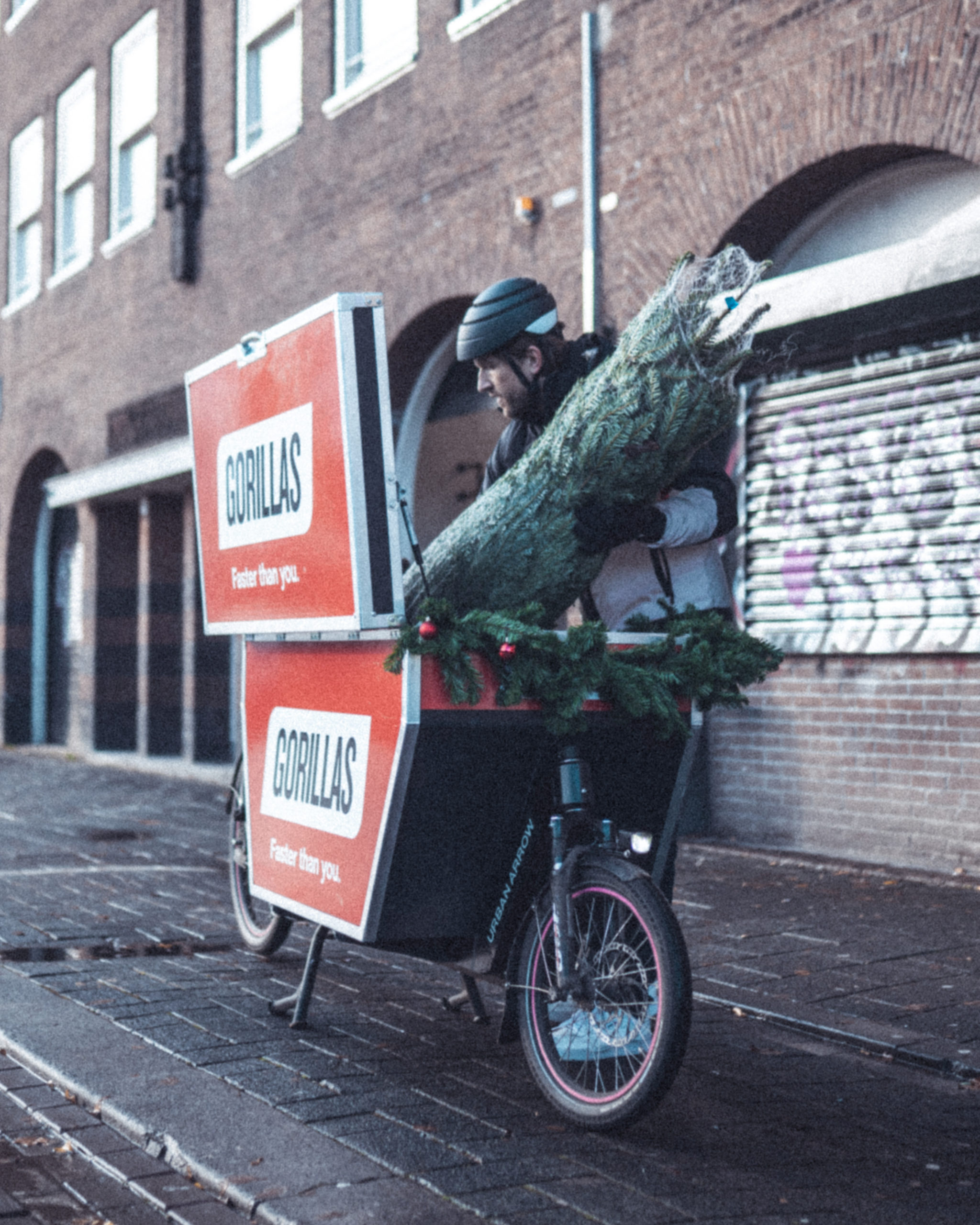 Een Gorillas-bezorger levert een kerstboom af. 