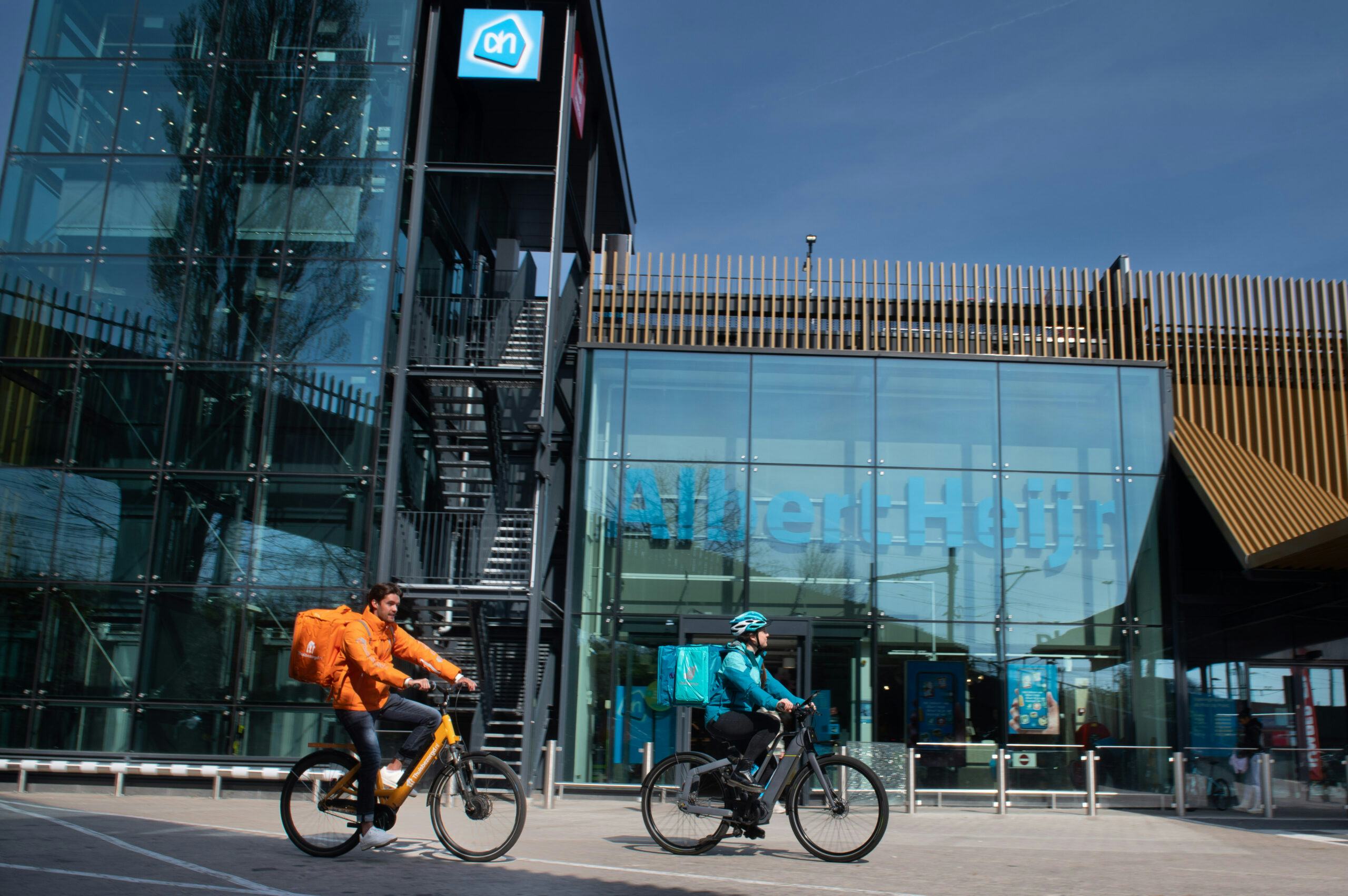 Bezorgers van Thuisbezorgd.nl en Deliveroo bij een AH-filiaal. Foto: Albert Heijn