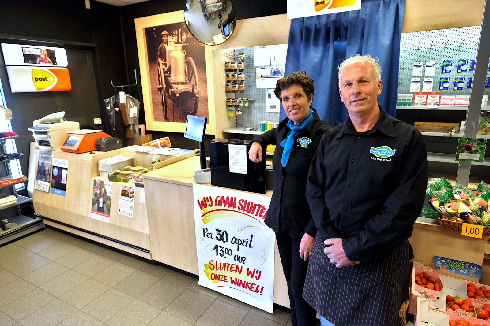 Anno en Bella in hun Dagwinkel, met linksachter de foto van opa die met handkar en melkbussen rondging. Foto: Distrifood.