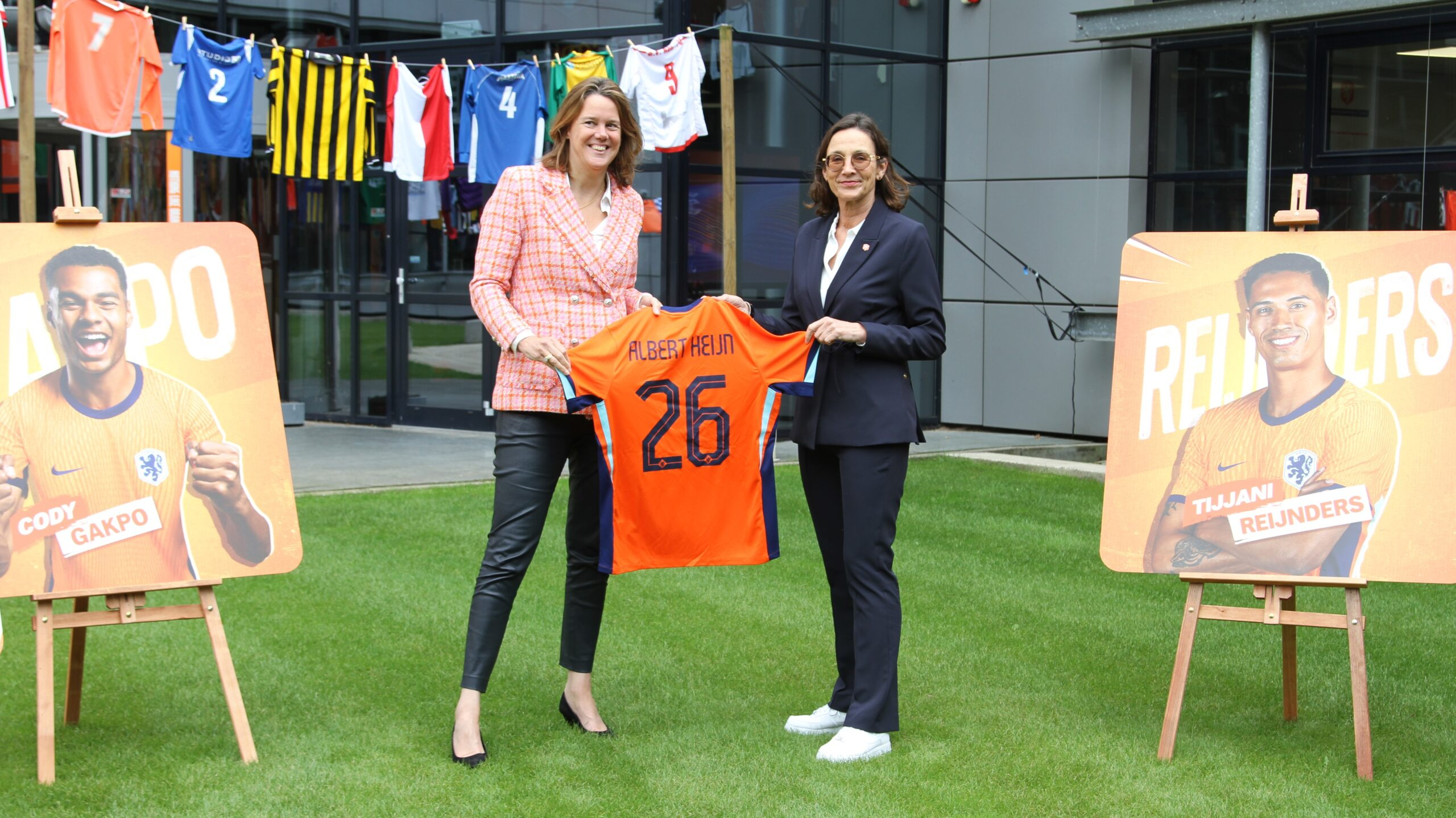 Albert Heijn-ceo Marit van Egmond en directeur betaald voetbal bij de KNVB Marianne van Leeuwen tonen het Oranje-shirt met rugnummer 26, verwijzend naar de duur van de verlengde samenwerking. Foto: Distrifood