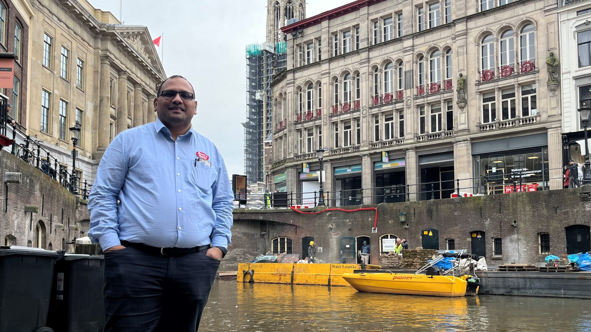 Boon’s Markt-ondernemer Nawin Harpal poseert pal naast zijn supermarkt in het centrum van Utrecht, met op de achtergrond de Domtoren. Foto: Distrifood