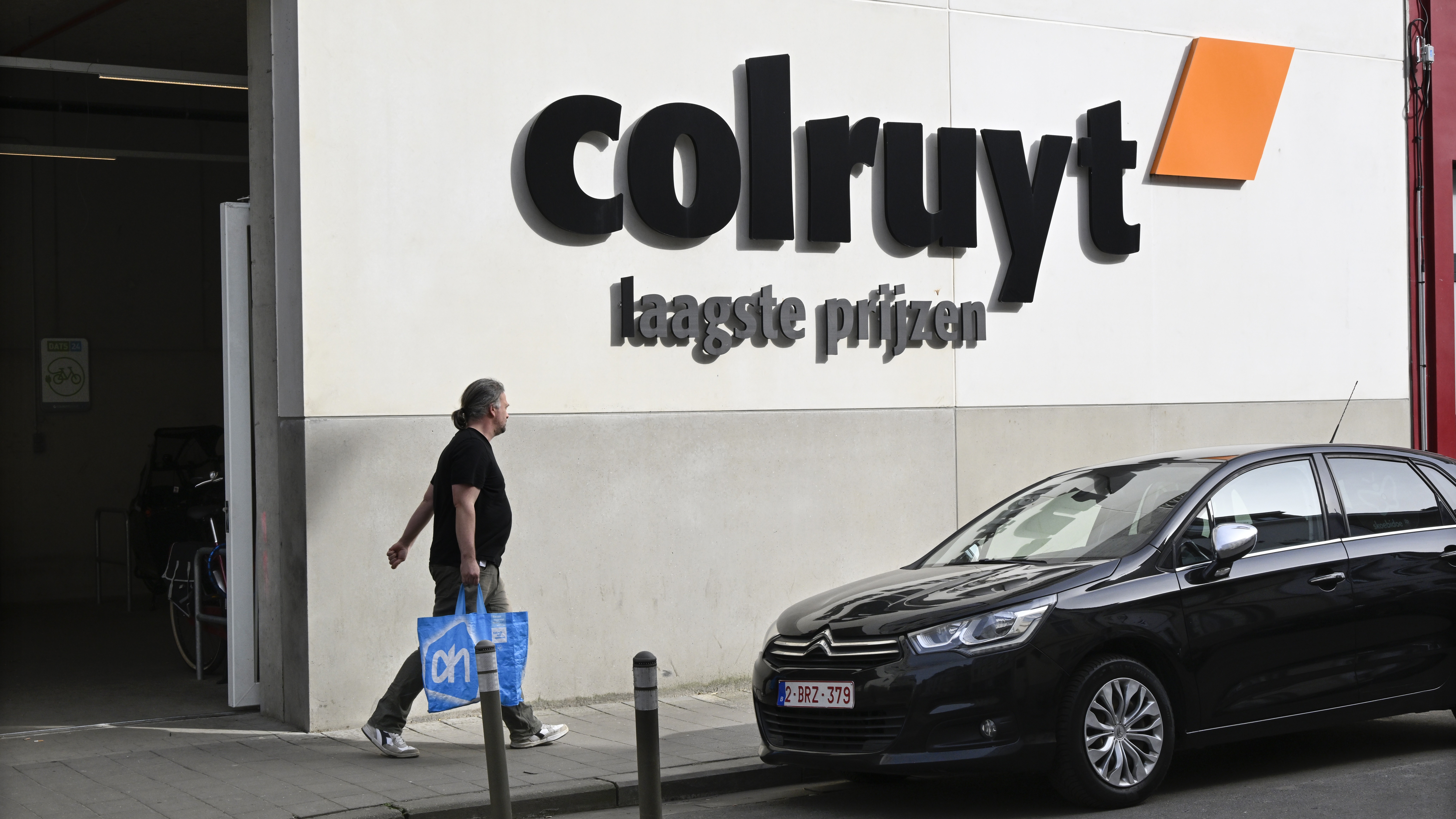 Klant met Albert Heijn-tas wandelt langs een Colruyt in Antwerpen. Foto: ANP