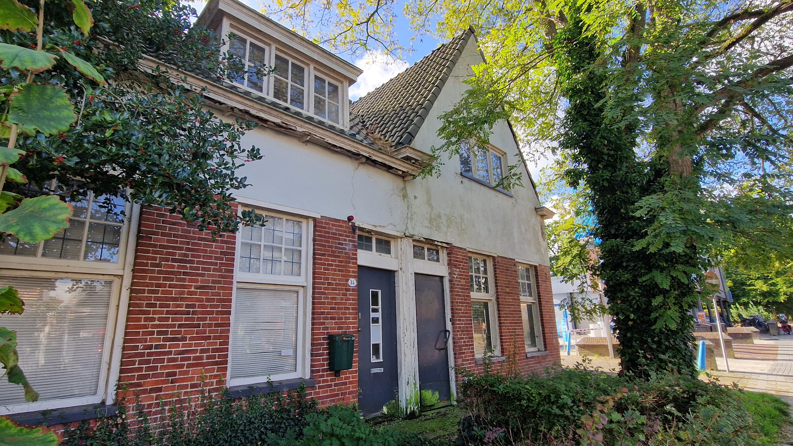 De 2 verkrotte huizen staan pal naast de parkeerplaats van een AH-filiaal. Foto: Distrifood